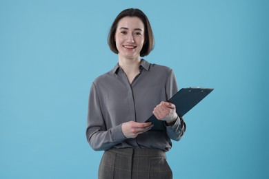 Photo of Portrait of young secretary with clipboard on light blue background