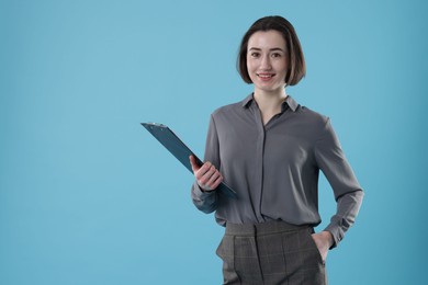 Photo of Portrait of young secretary with clipboard on light blue background. Space for text