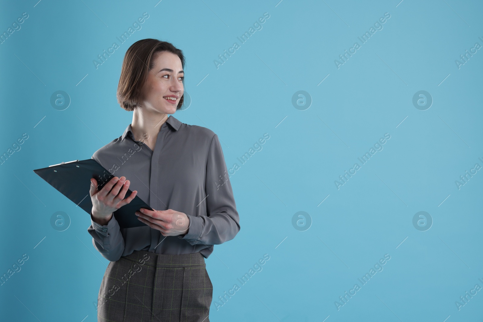 Photo of Portrait of young secretary with clipboard on light blue background. Space for text