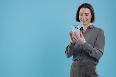 Photo of Young secretary using smartphone on light blue background. Space for text