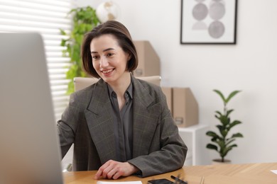 Photo of Smiling secretary working on computer at table in office