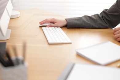 Photo of Secretary working on computer at wooden table indoors, closeup