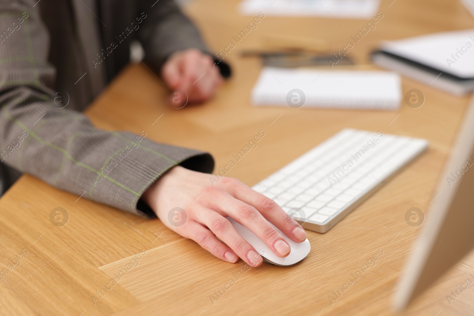 Photo of Secretary working on computer at wooden table indoors, closeup