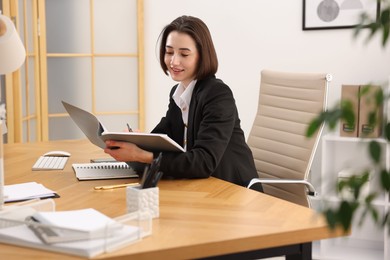 Smiling secretary with folder at table in office