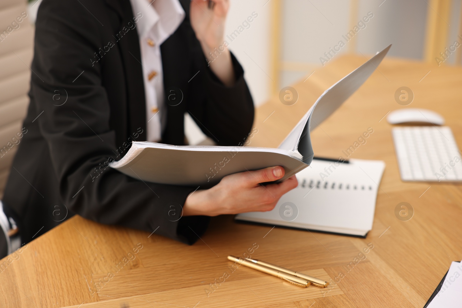 Photo of Secretary with folder at wooden table in office, closeup