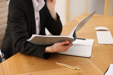 Photo of Secretary with folder at wooden table in office, closeup