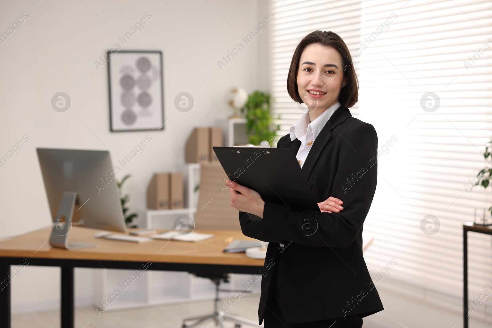 Photo of Portrait of smiling secretary with clipboard in office. Space for text