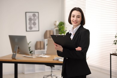 Portrait of smiling secretary with clipboard in office. Space for text