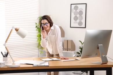 Photo of Secretary talking on smartphone at table in office