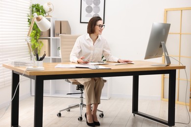 Photo of Smiling secretary working on computer at table in office