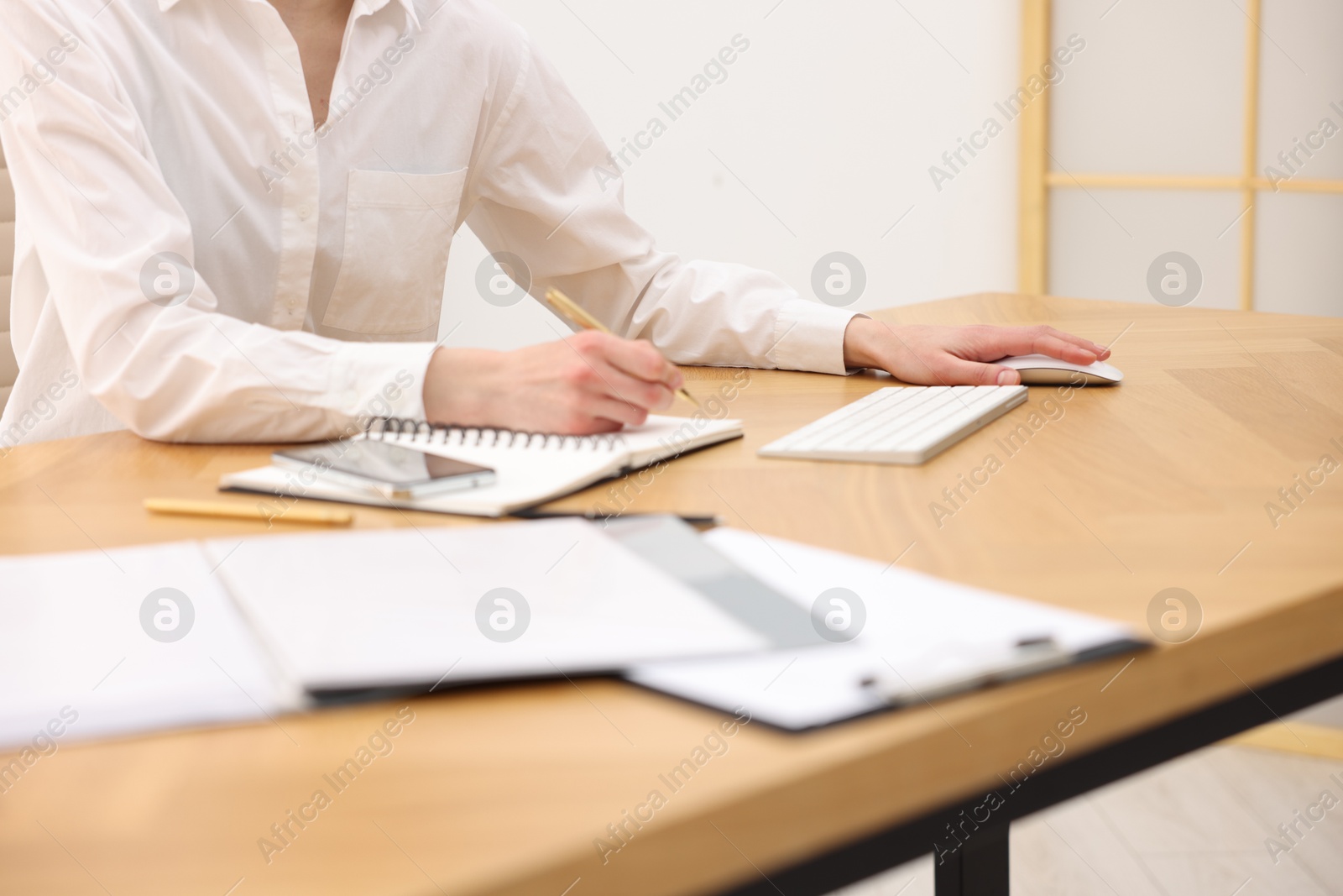 Photo of Secretary taking notes at wooden table in office, closeup