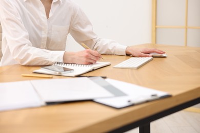 Photo of Secretary taking notes at wooden table in office, closeup