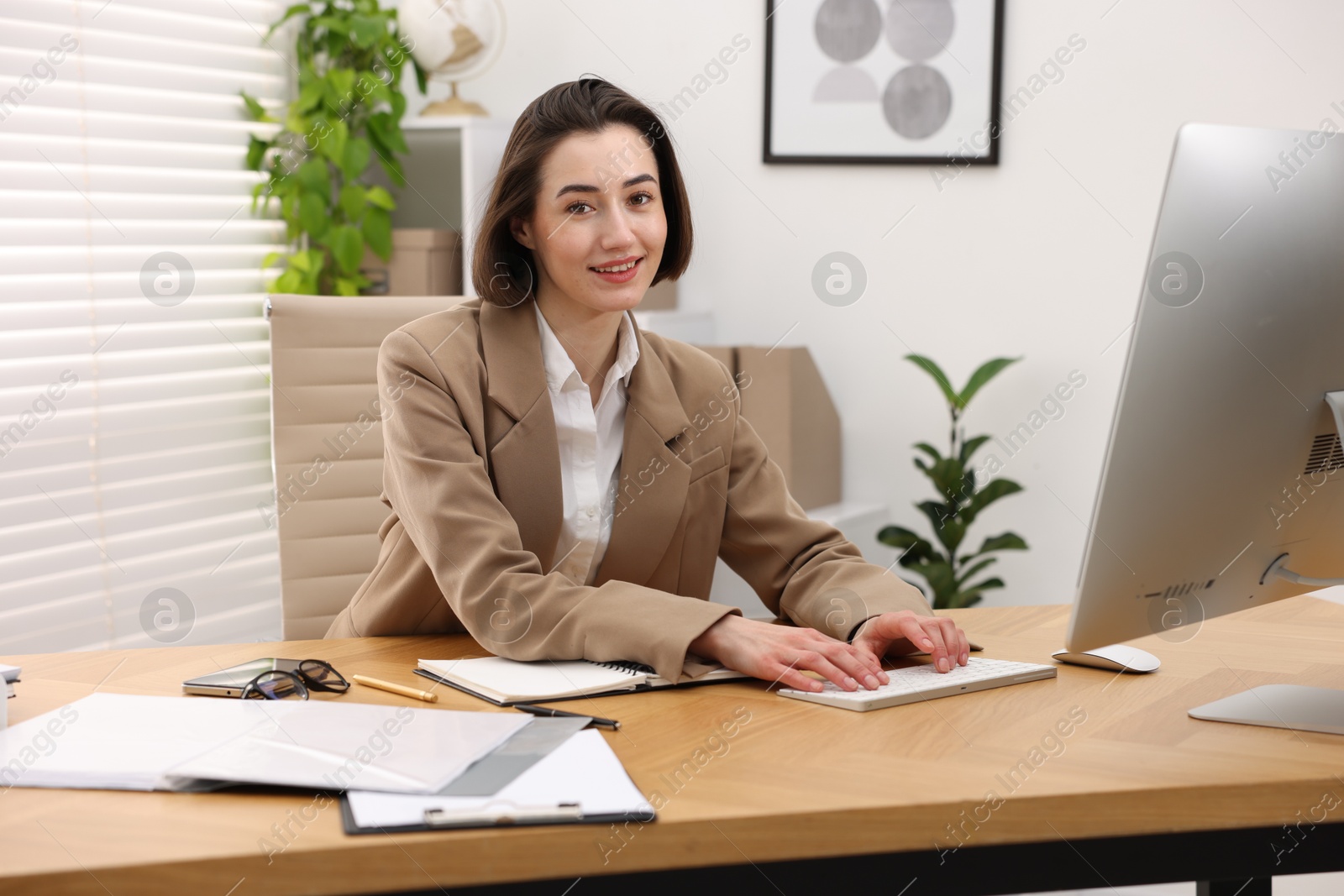 Photo of Smiling secretary working on computer at table in office