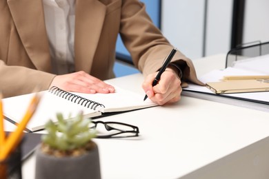 Secretary taking notes at table in office, closeup