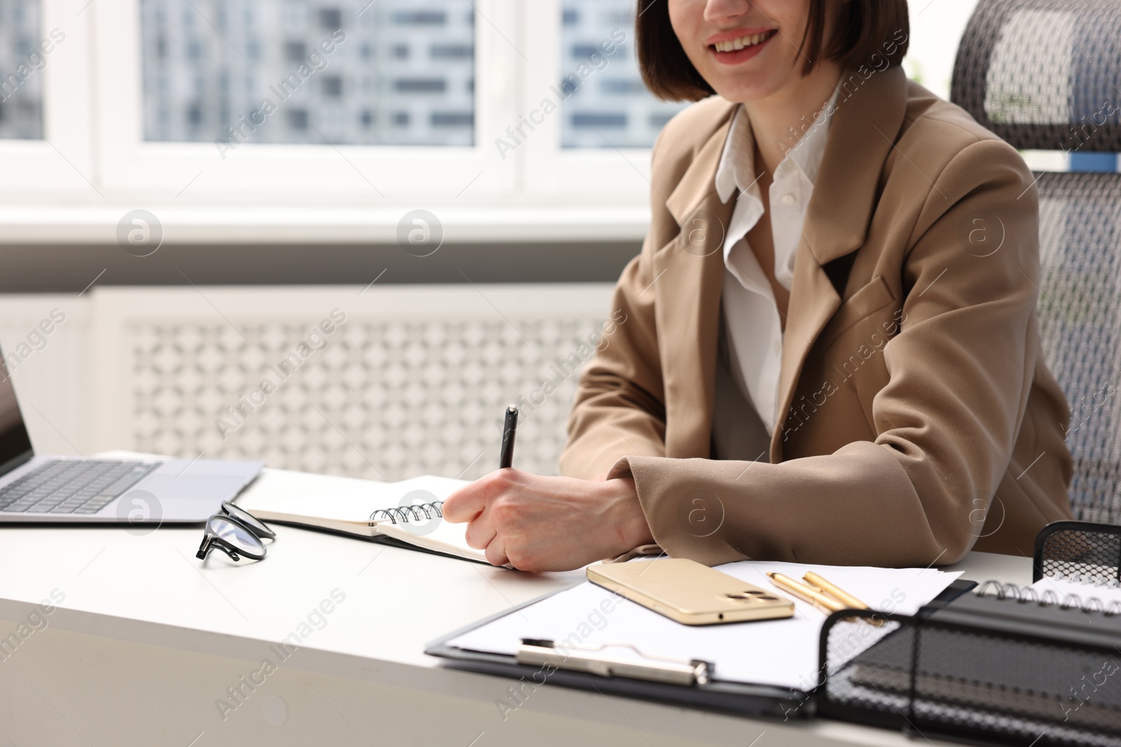 Photo of Secretary taking notes at table in office, closeup