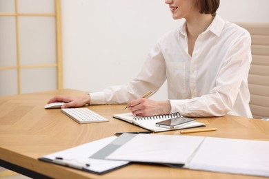 Secretary working at wooden table indoors, closeup