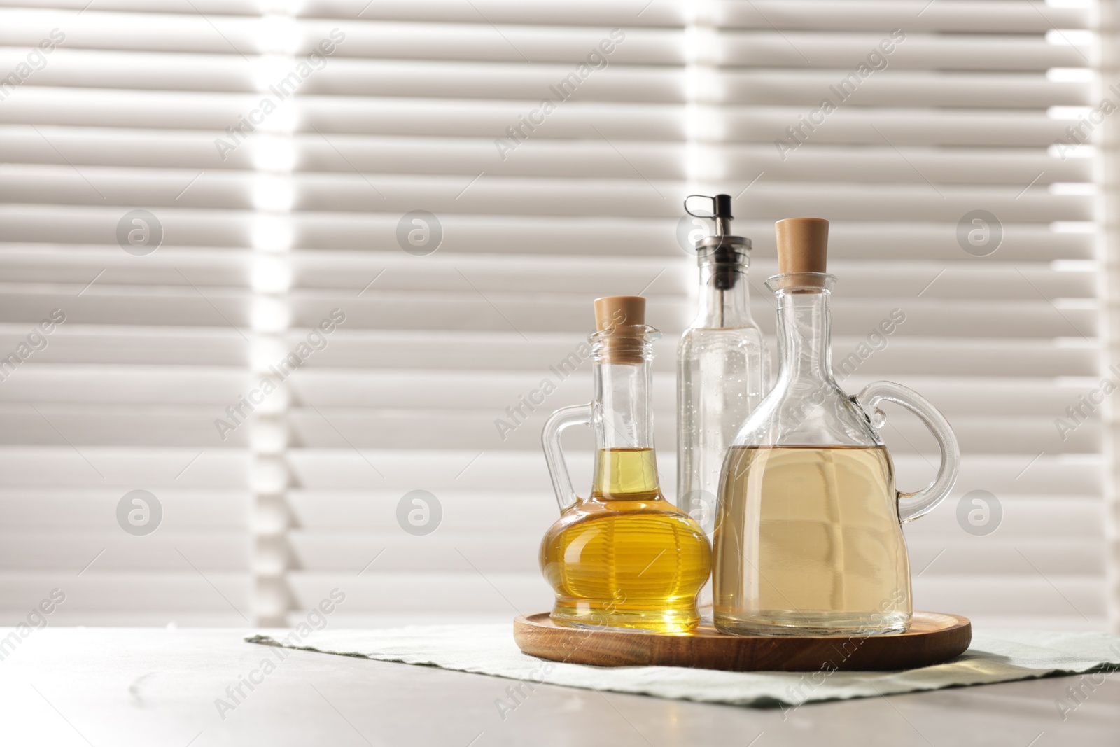 Photo of Oil and vinegar on table in kitchen. Space for text