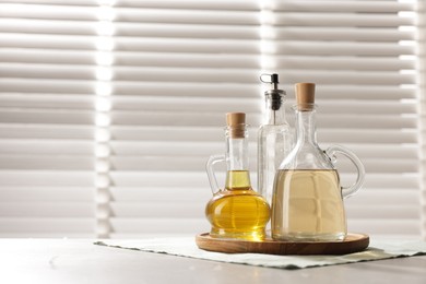 Photo of Oil and vinegar on table in kitchen. Space for text