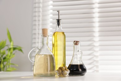 Photo of Salad dressings and olives on table in kitchen