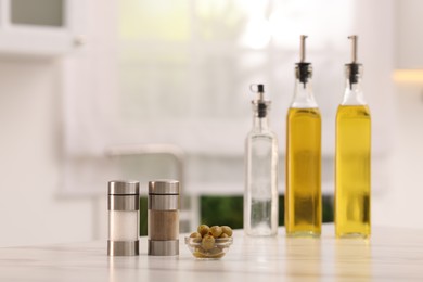 Photo of Salad dressings, spices and olives on table in kitchen. Space for text