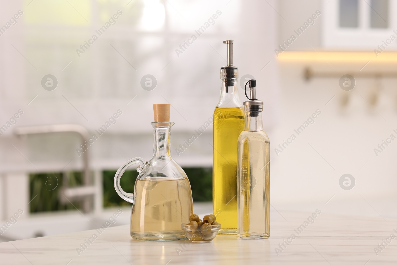 Photo of Salad dressings and olives on table in kitchen