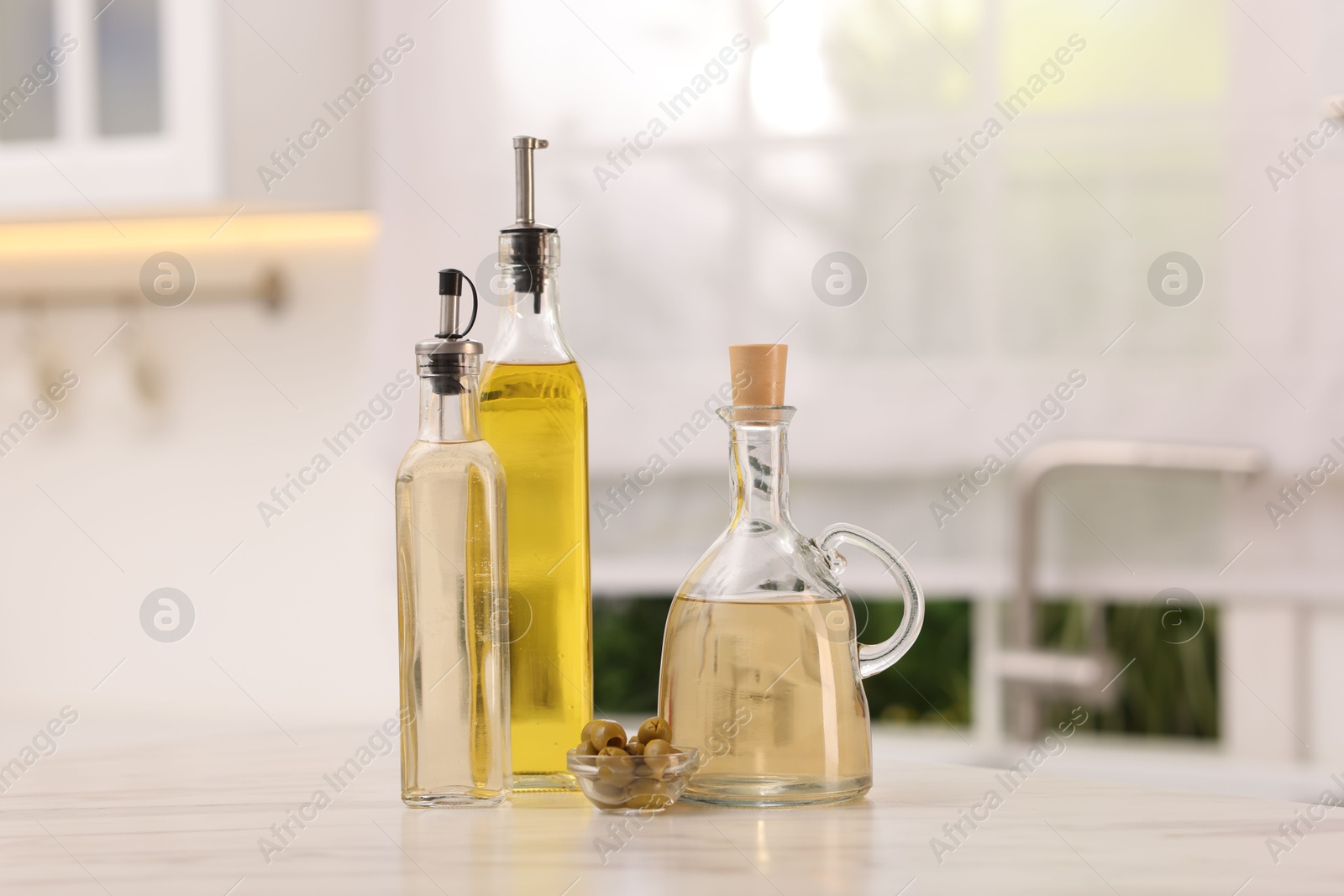 Photo of Salad dressings and olives on table in kitchen