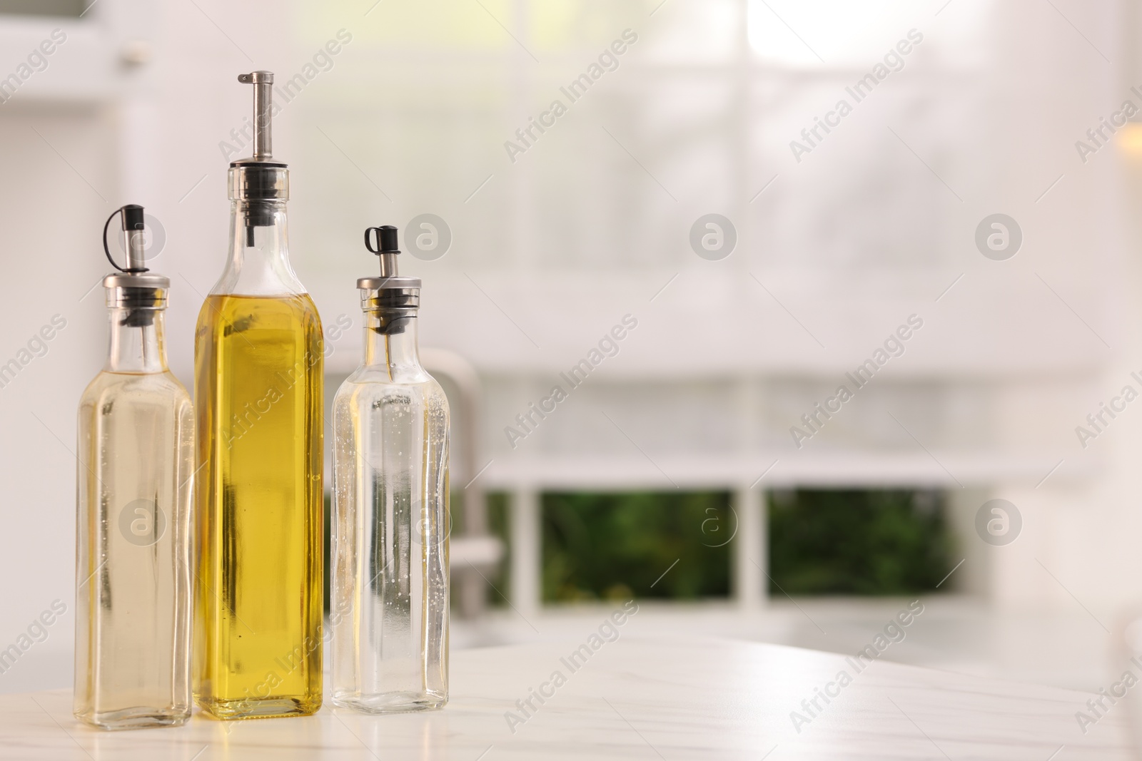 Photo of Oil and vinegar on table in kitchen. Space for text