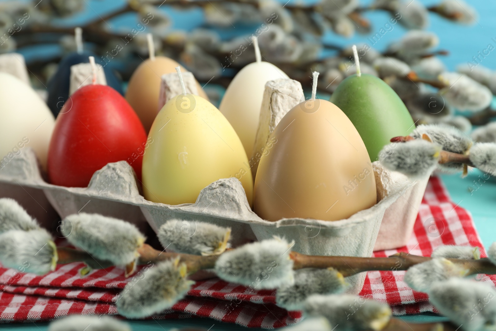 Photo of Colorful egg-shaped candles in carton on table, closeup. Easter decor