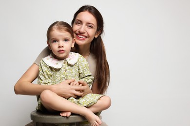 Photo of Portrait of happy mother with her cute little daughter on grey background, space for text