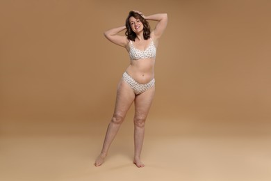 Photo of Beautiful woman in underwear on dark beige background. Cellulite problem