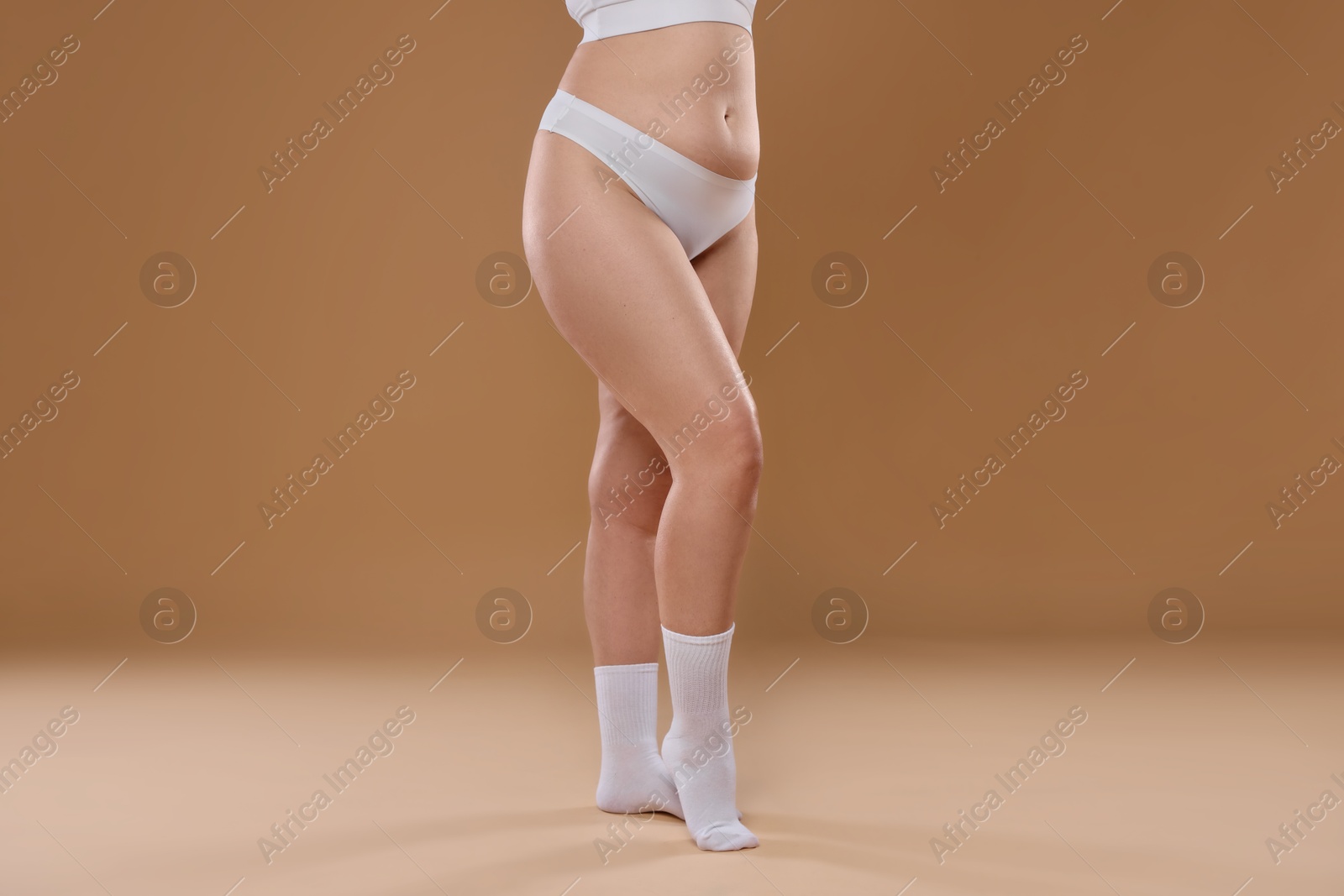 Photo of Woman with cellulite on dark beige background, closeup