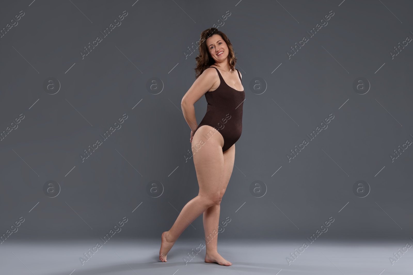 Photo of Beautiful woman in bodysuit on dark grey background. Cellulite problem