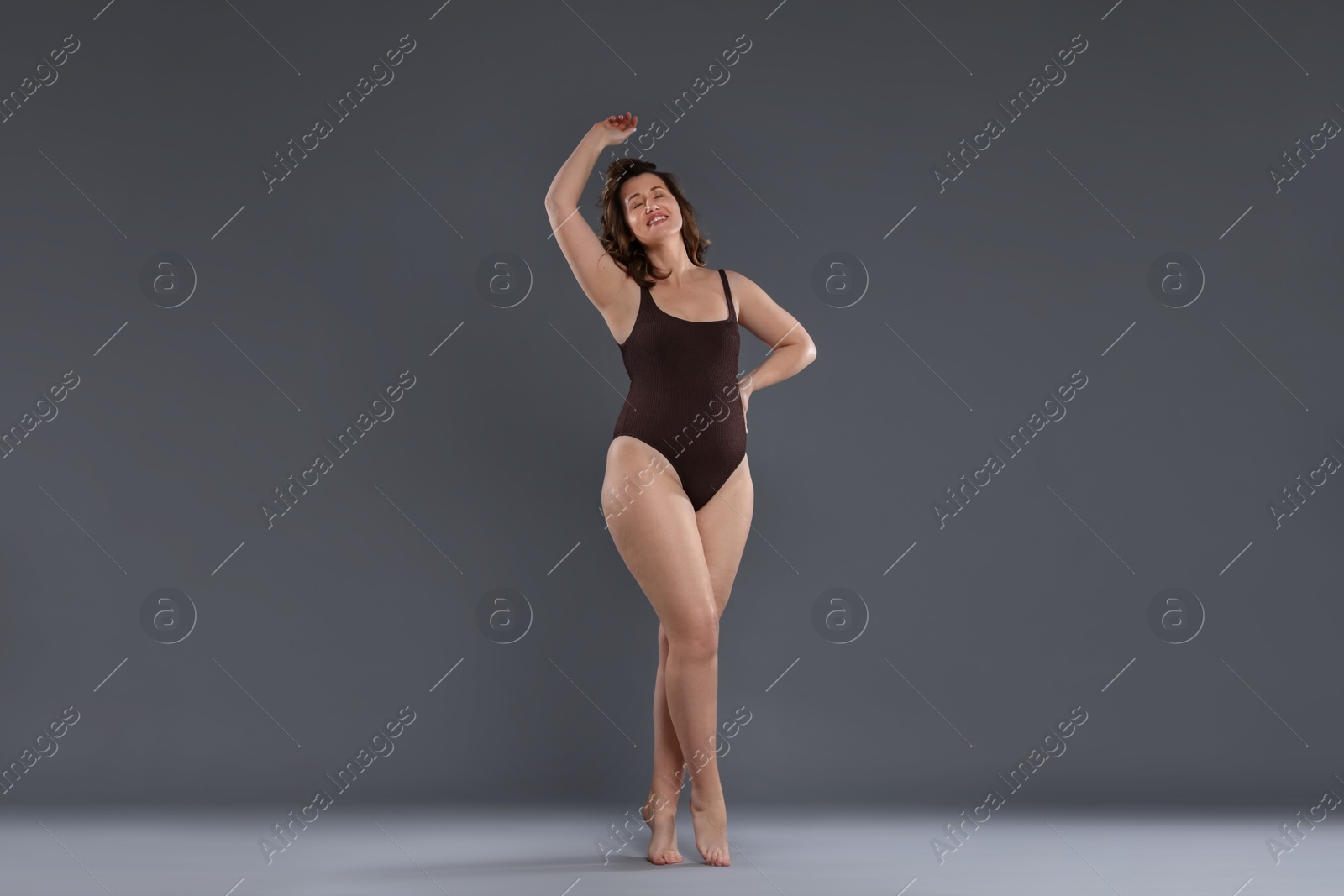 Photo of Beautiful woman in bodysuit on dark grey background. Cellulite problem