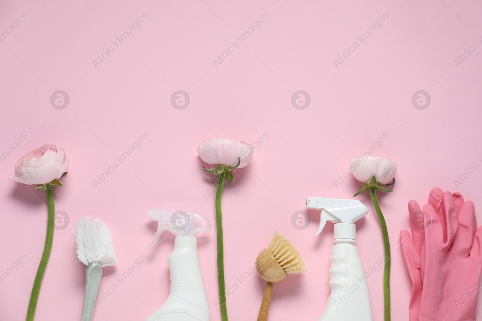 Photo of Spring cleaning. Detergents, supplies and flowers on pink background, flat lay. Space for text