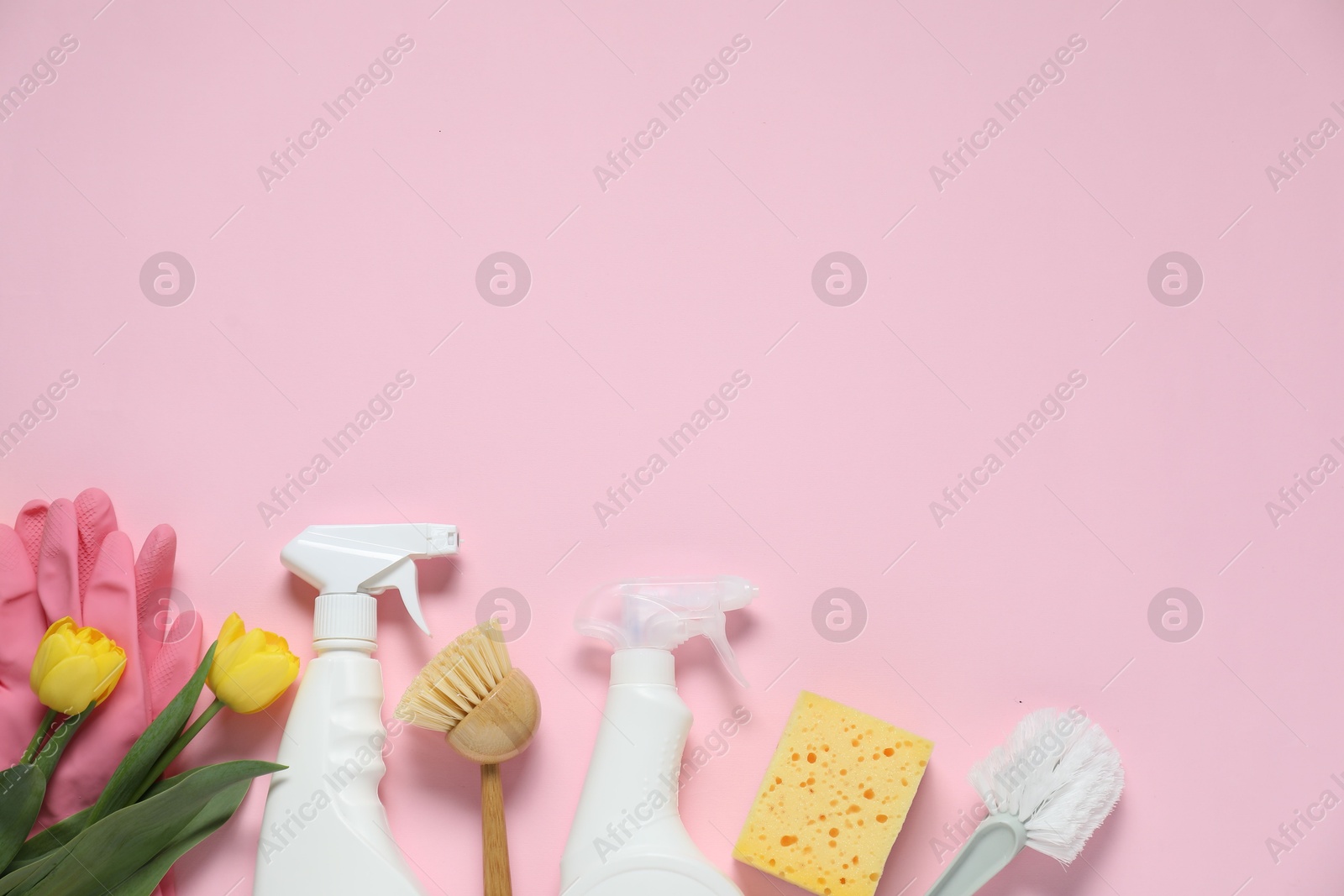 Photo of Spring cleaning. Detergents, supplies and tulips on pink background, flat lay. Space for text