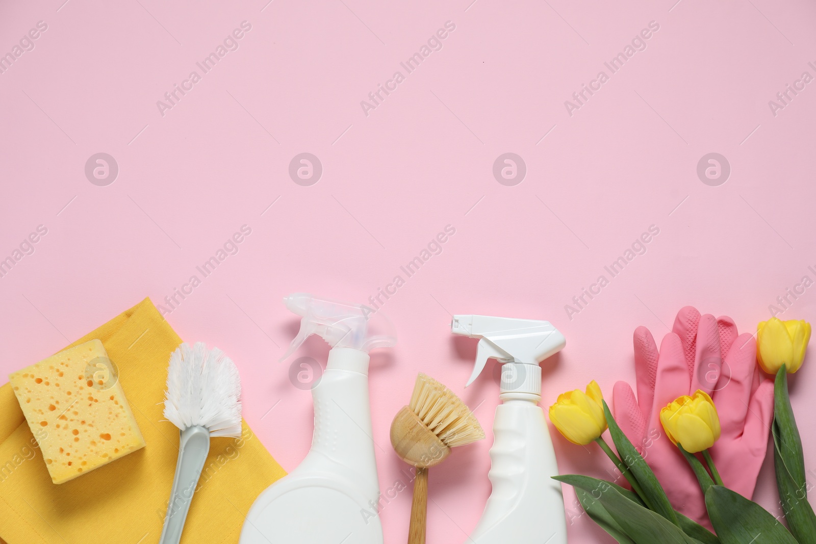 Photo of Spring cleaning. Detergents, supplies and tulips on pink background, flat lay. Space for text