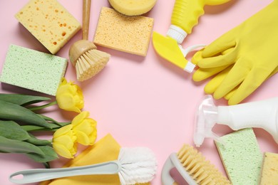 Photo of Spring cleaning. Detergents, supplies and tulips on pink background, flat lay. Space for text