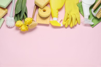 Photo of Spring cleaning. Detergents, supplies and tulips on pink background, flat lay. Space for text