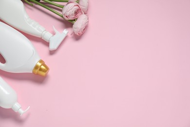 Photo of Spring cleaning. Bottles with detergents and flowers on pink background, flat lay. Space for text