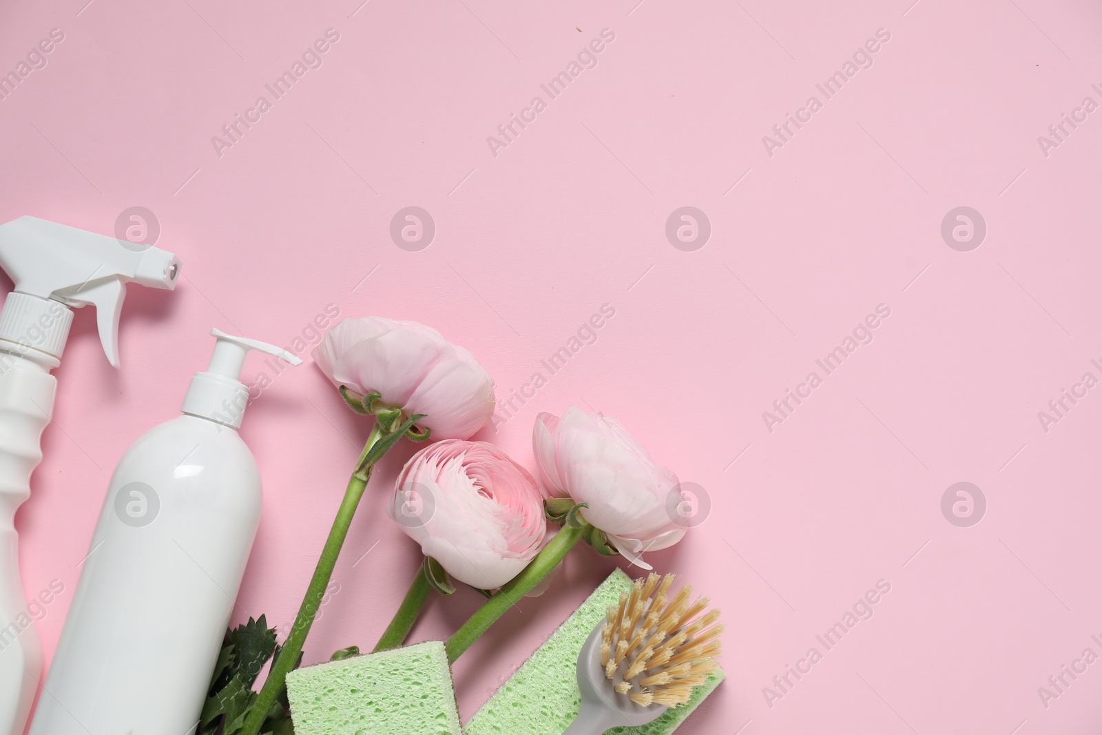 Photo of Spring cleaning. Detergents, supplies and flowers on pink background, flat lay. Space for text