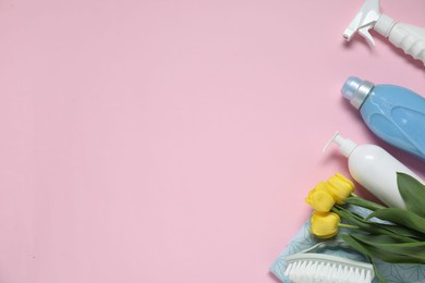 Photo of Spring cleaning. Detergents, supplies and tulips on pink background, flat lay. Space for text