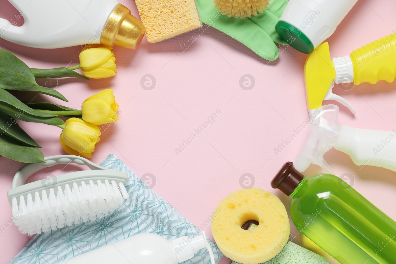 Photo of Spring cleaning. Detergents, supplies and tulips on pink background, flat lay. Space for text