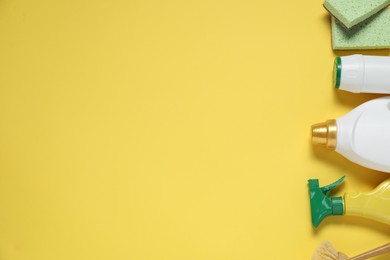 Photo of Detergents and supplies on yellow background, flat lay. Space for text