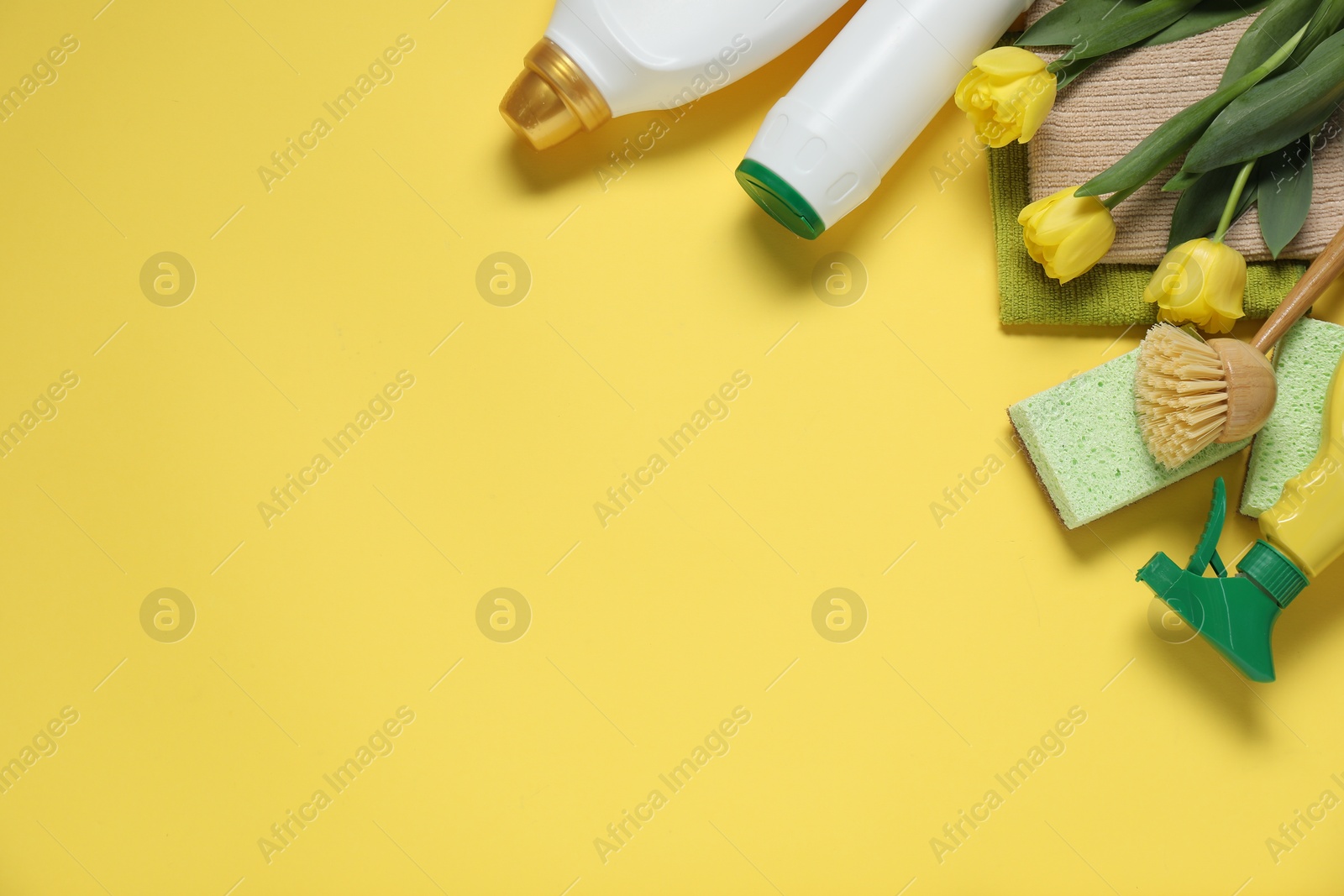 Photo of Spring cleaning. Detergents, supplies and tulips on yellow background, flat lay. Space for text