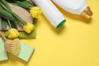 Photo of Spring cleaning. Detergents, supplies and tulips on yellow background, flat lay. Space for text