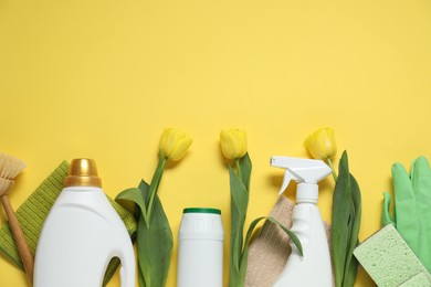 Photo of Spring cleaning. Detergents, supplies and tulips on yellow background, flat lay. Space for text