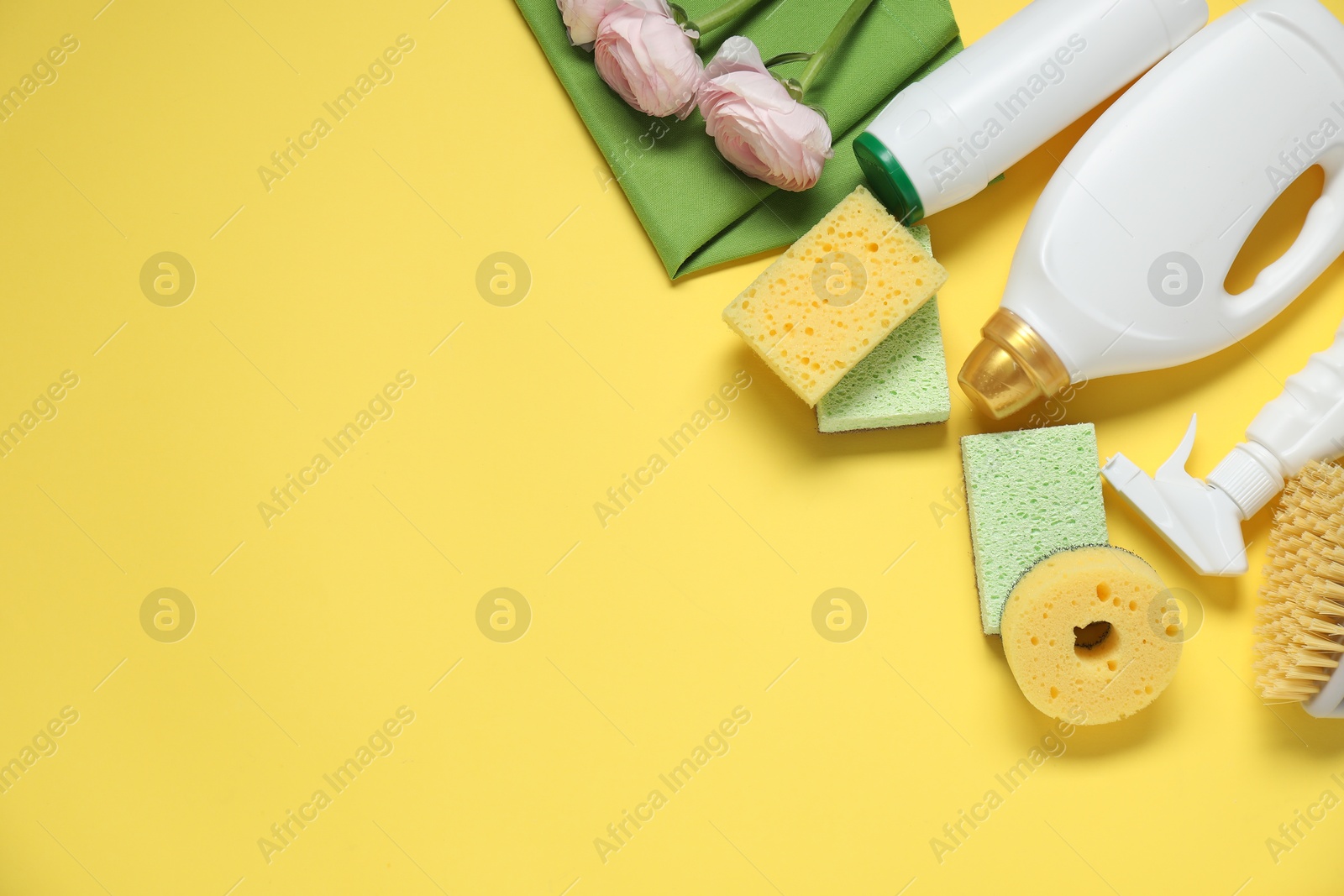 Photo of Spring cleaning. Detergents, supplies and flowers on yellow background, flat lay. Space for text