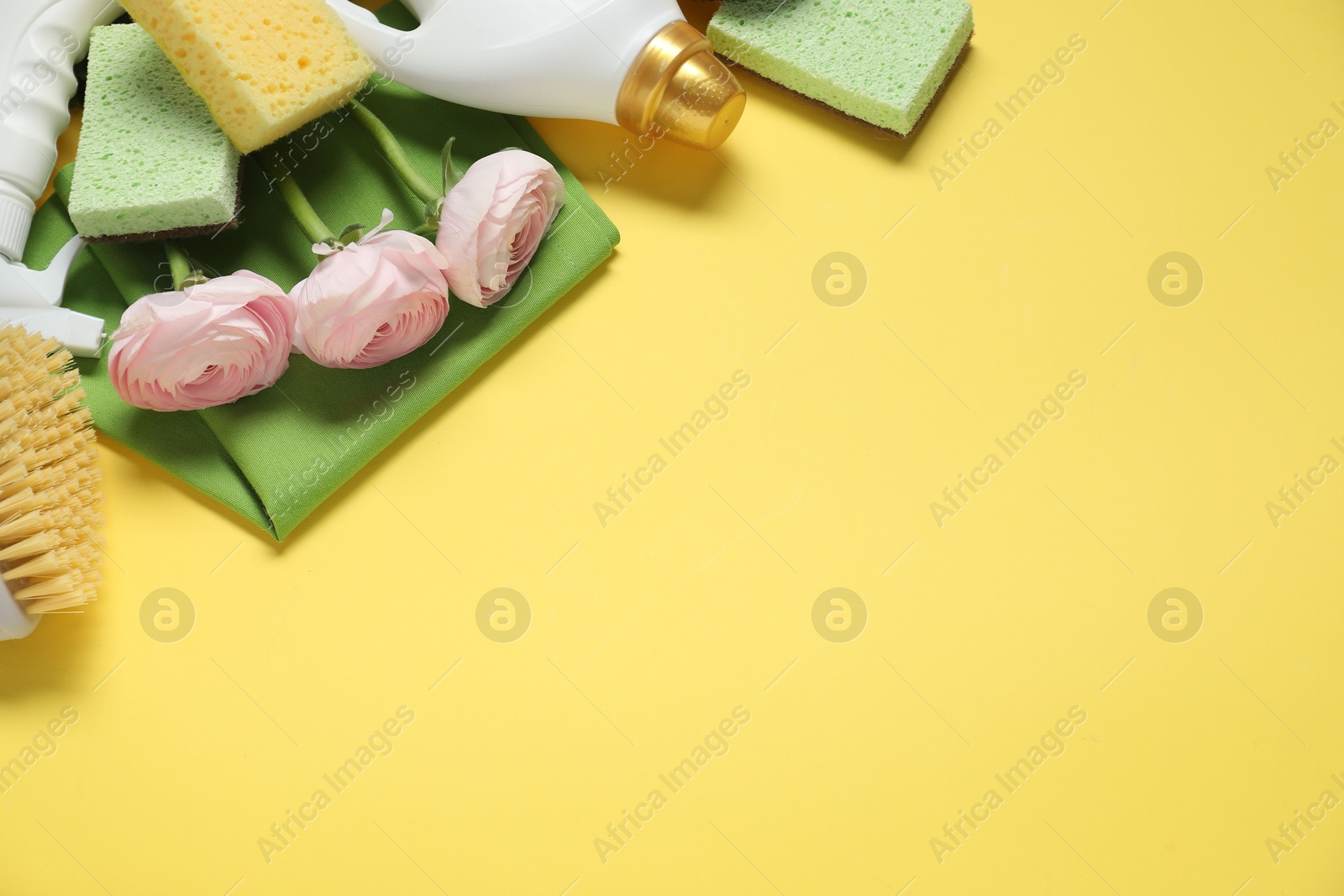 Photo of Spring cleaning. Detergents, supplies and flowers on yellow background, flat lay. Space for text