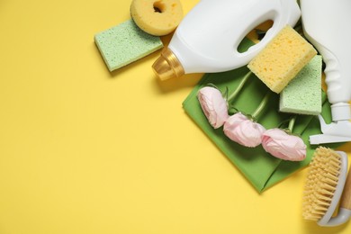 Photo of Spring cleaning. Detergents, supplies and flowers on yellow background, flat lay. Space for text