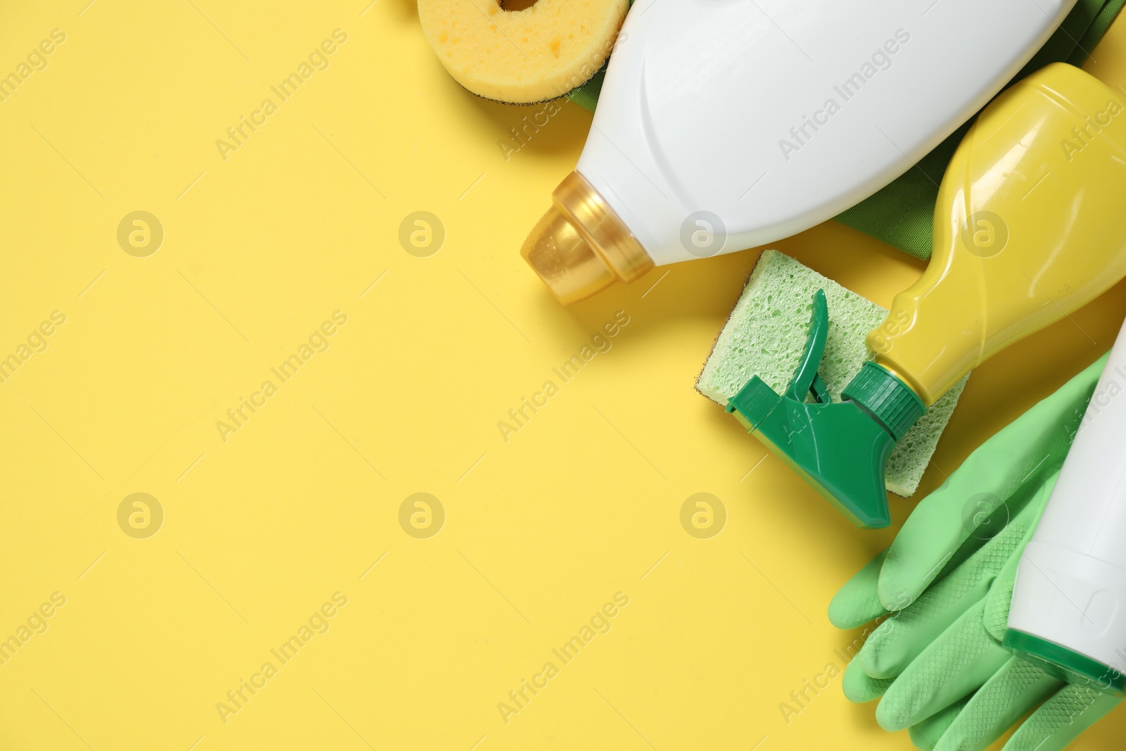 Photo of Detergents and supplies on yellow background, flat lay. Space for text